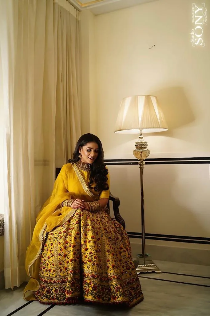 Full bridal look in a gold embellished lehenga, seated portrait