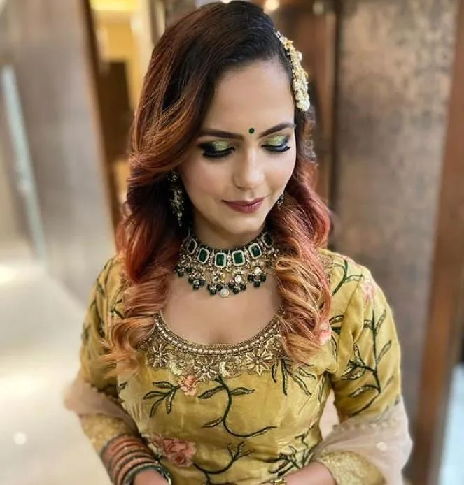 Festive green-and-gold eye makeup with bindi and jewellery, yellow outfit